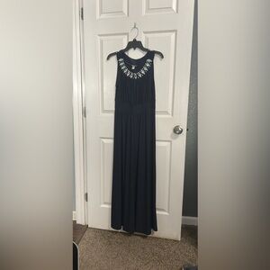 Navy blue dress that goes all the way to the ground and has jewelry on it.